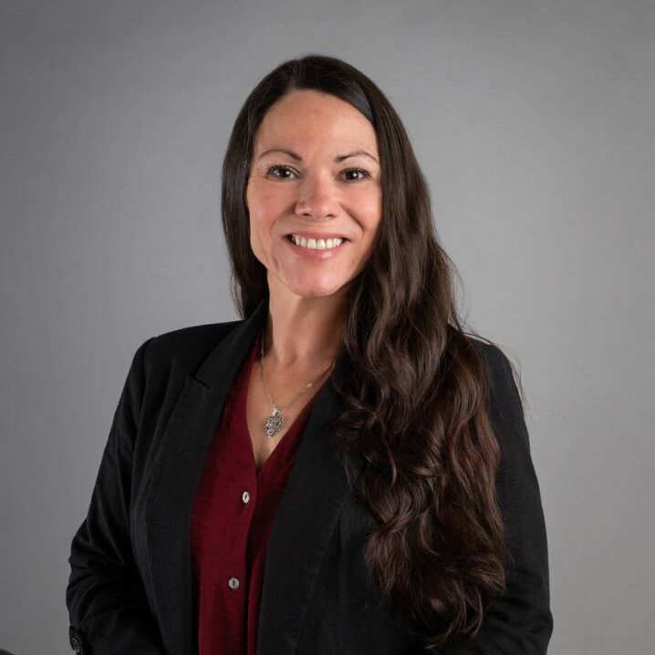 Smiling woman in blazer against gray background